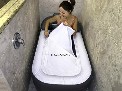 Person using an inflatable bathtub in a small tiled area.